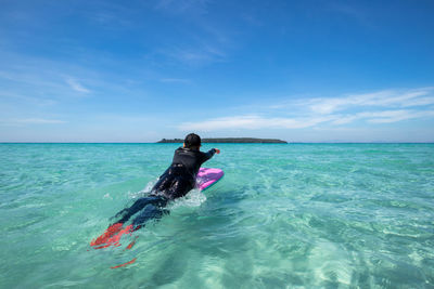 Rear view of man in sea against sky