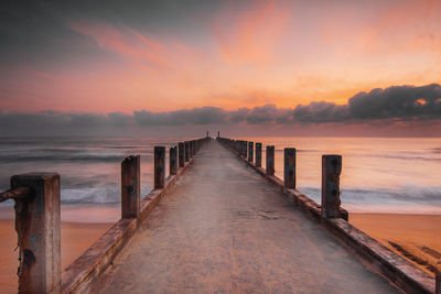 Pier over sea against sky during sunset
