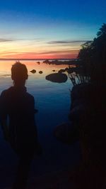 Silhouette man on beach against sky during sunset