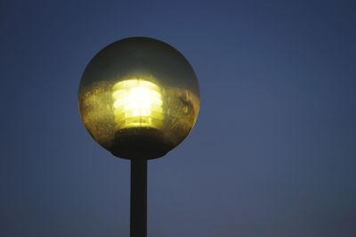 Low angle view of illuminated lamp against blue sky