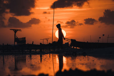Silhouette man on boat against sky during sunset