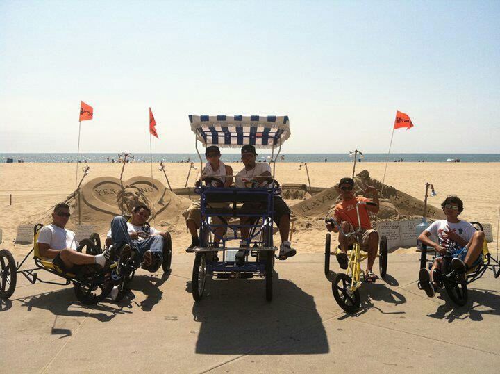 beach, sea, lifestyles, leisure activity, sand, men, horizon over water, shore, vacations, person, large group of people, sky, clear sky, bicycle, casual clothing, mixed age range, day, full length, flag