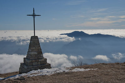 Cross on mountain against cloudscape