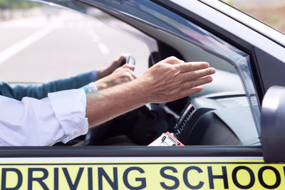 Cropped hand of instructor teaching driving in car