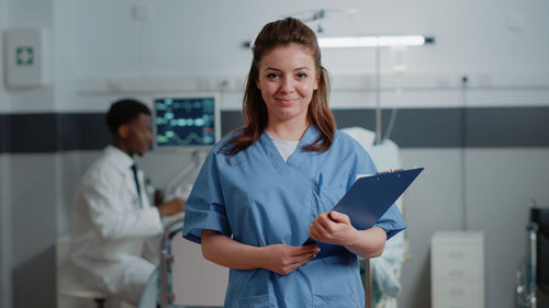Portrait of smiling nurse holding file folder