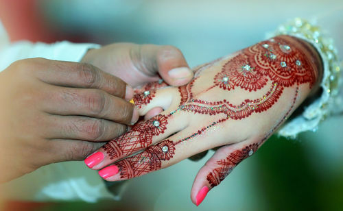 Close-up of groom putting wedding ring on bride finger