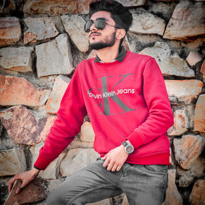 Full length of young man sitting against brick wall