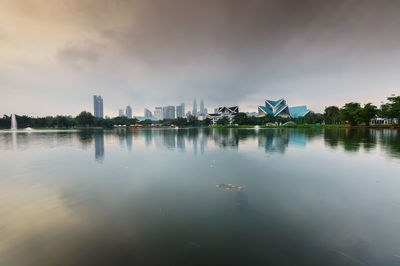 City at waterfront against cloudy sky