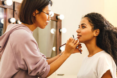 Beautician applying make-up on woman in beauty spa