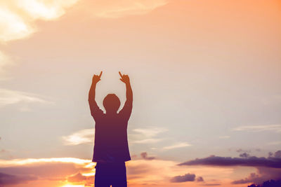 Rear view of silhouette man standing against sky during sunset