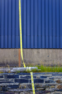 Yellow tape against blue metal fence 