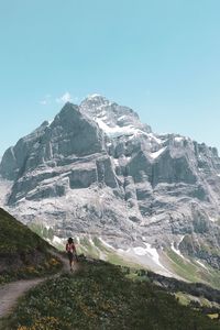 Rear view of man standing on mountain against sky