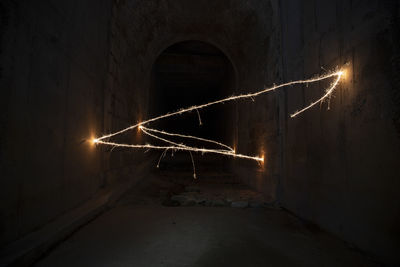 Low angle view of illuminated lights in tunnel at night