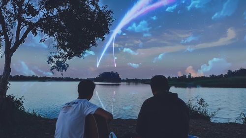 Rear view of people on lake against sky