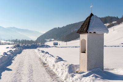 Small mountain chapel covered with wooden shingle. in the background snow-capped mountains, blue sky