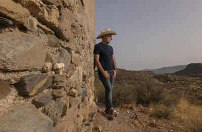 Portrait of adult man in cowboy hat standing against wall in desert. almeria, spain