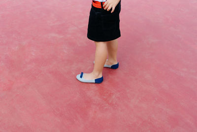 Low section of woman standing at tennis court