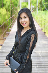 Portrait of smiling woman standing on railing