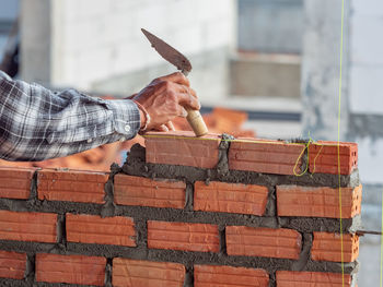 Man holding umbrella on brick wall