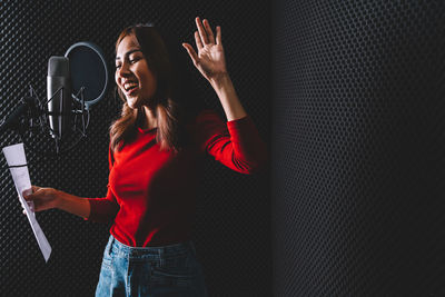 Young woman singing song by microphone 