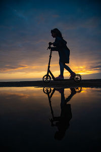 Silhouette man by lake against sky during sunset