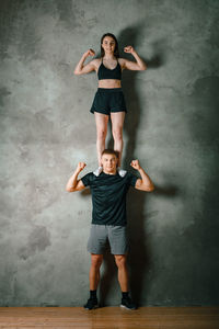 A man and a woman athletes stand on top of each other on a gray background. gymnastics workouts