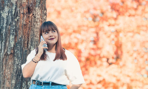 Young woman looking away while standing outdoors