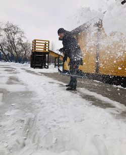 Man removing snow covered road during winter