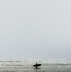 Silhouette man on sea against clear sky