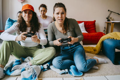 Young female friends playing video game at home