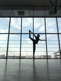 Full length of woman stretching against glass window