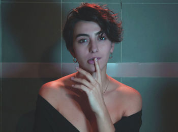 Portrait of young woman standing against wall