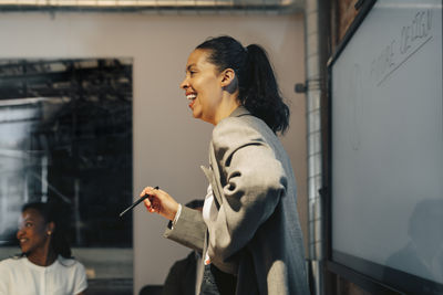 Side view of happy businesswoman laughing in meeting with colleagues at office