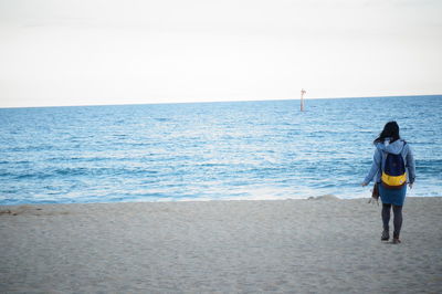 Rear view of man looking at sea against clear sky