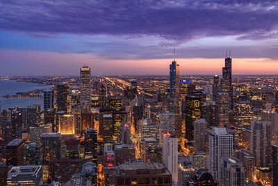 Illuminated cityscape against sky during sunset