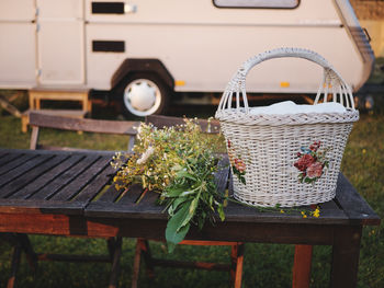 Close-up of basket and plants on wooden table at campsite