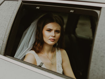 Portrait of a sad bride in a car in rainy weather.