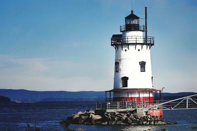 Lighthouse by sea against sky