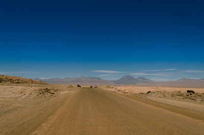 Road amidst desert against blue sky