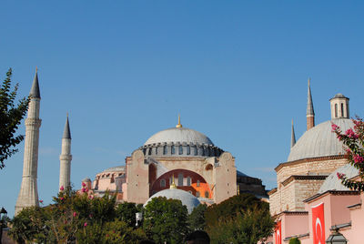 View of buildings in city against clear blue sky