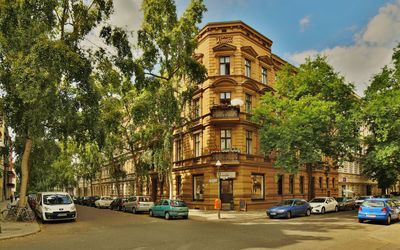 Cars on road by buildings against sky