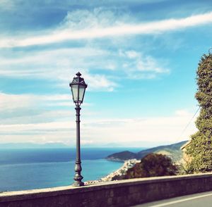 Street light by sea against sky