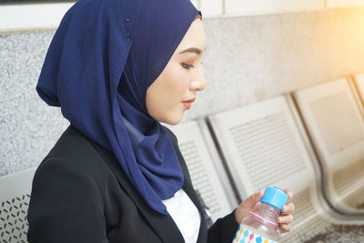 Portrait of young woman holding bottle