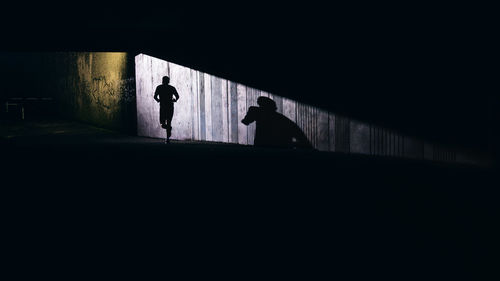 Silhouette people walking in tunnel