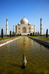 Low angle view of taj mahal in front of reflecting pool against clear sky