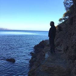 Man standing on beach against clear sky