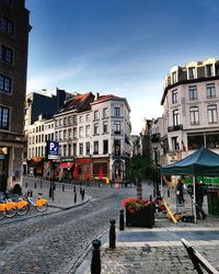 Street by buildings in town against sky