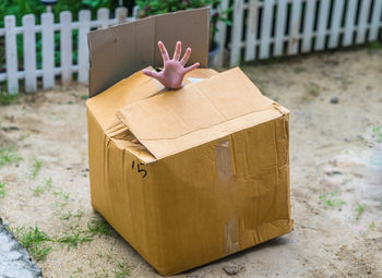 Cropped hand of person hiding in cardboard box