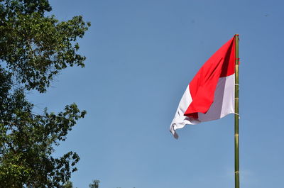 Low angle view of flag against clear blue sky