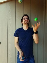 Man juggling while standing against wall